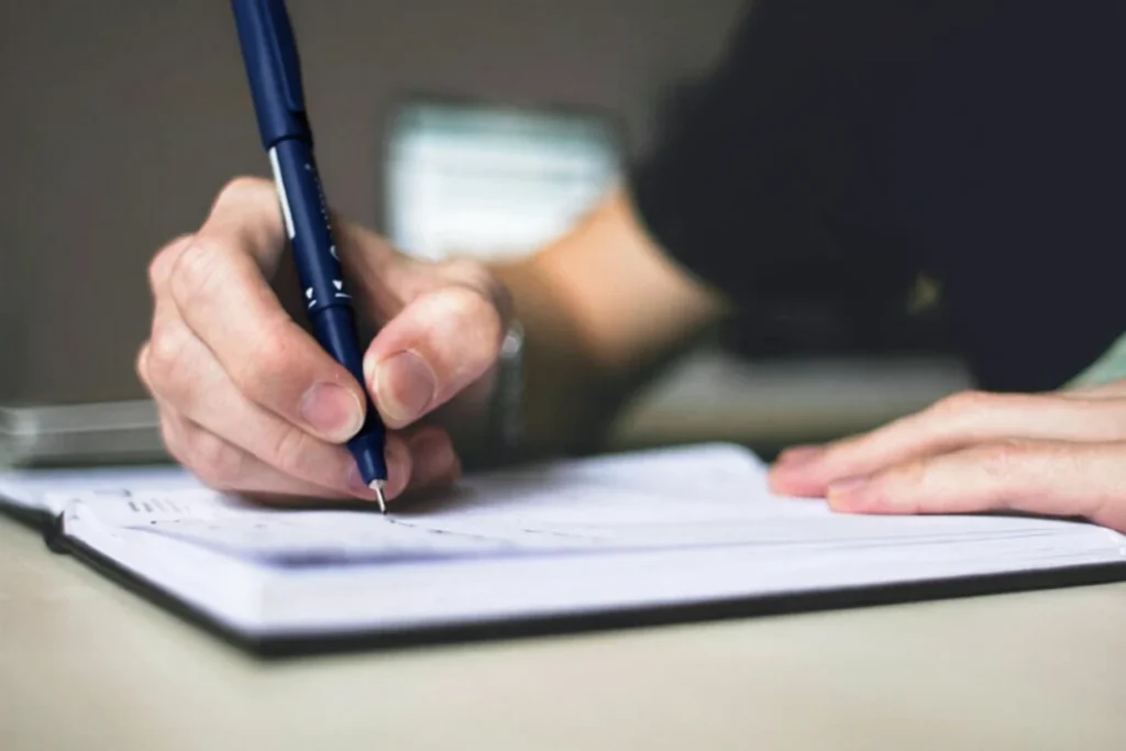 Close-up of a hand writing a Bipolar Emergency Plan in a notebook.